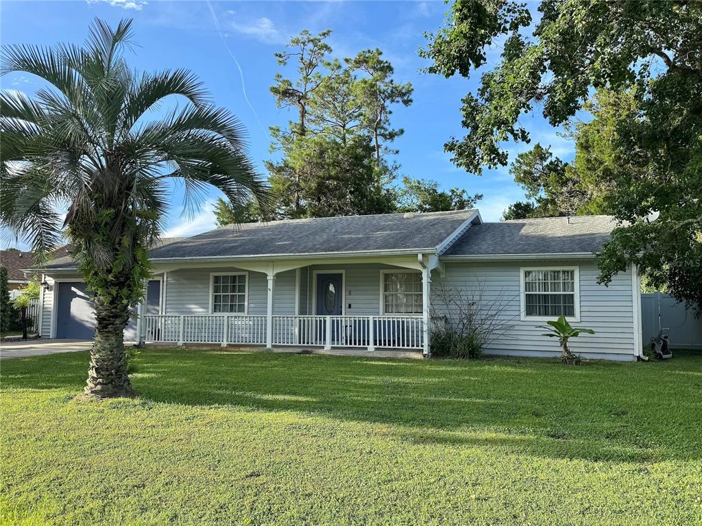 A light blue single-story house features a front porch with a white railing and palm tree — 5 BANNER LANE, PALM COAST, FL