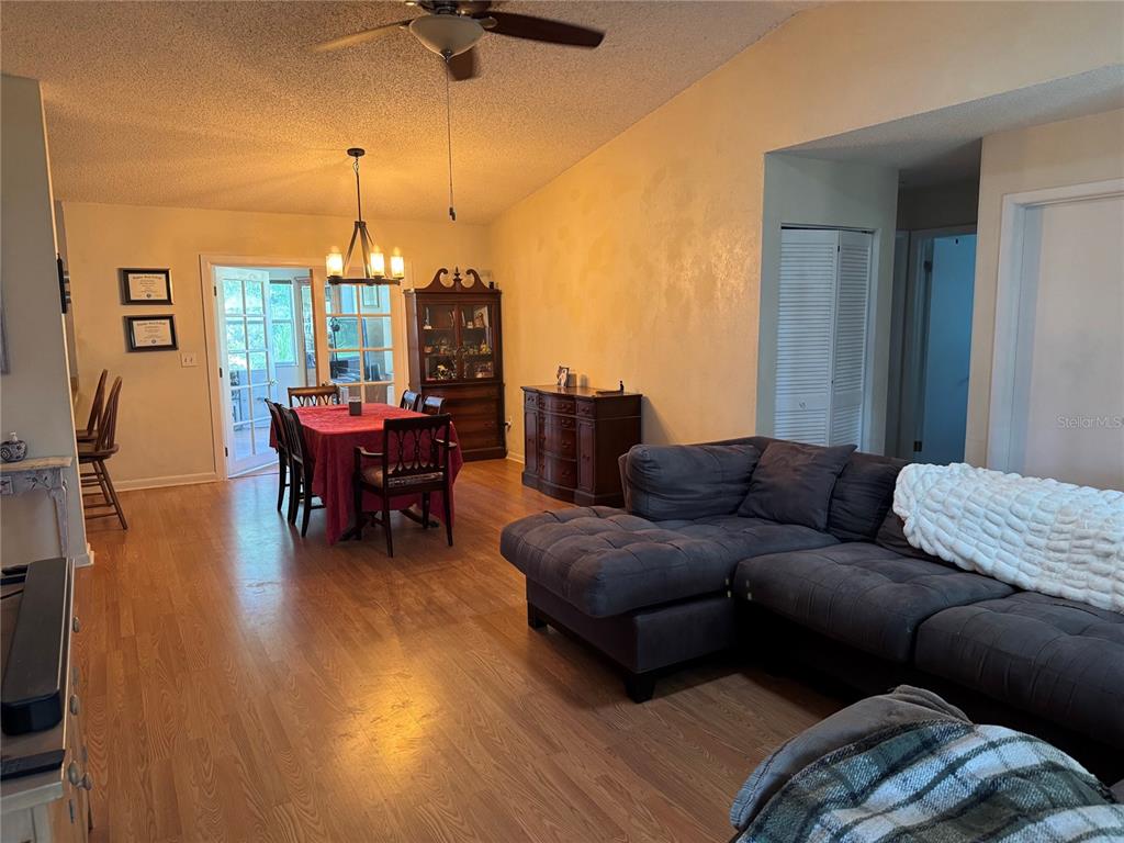 A living and dining room with hardwood floors, a dark sectional, and a red-clothed table — 5 BANNER LANE, PALM COAST, FL