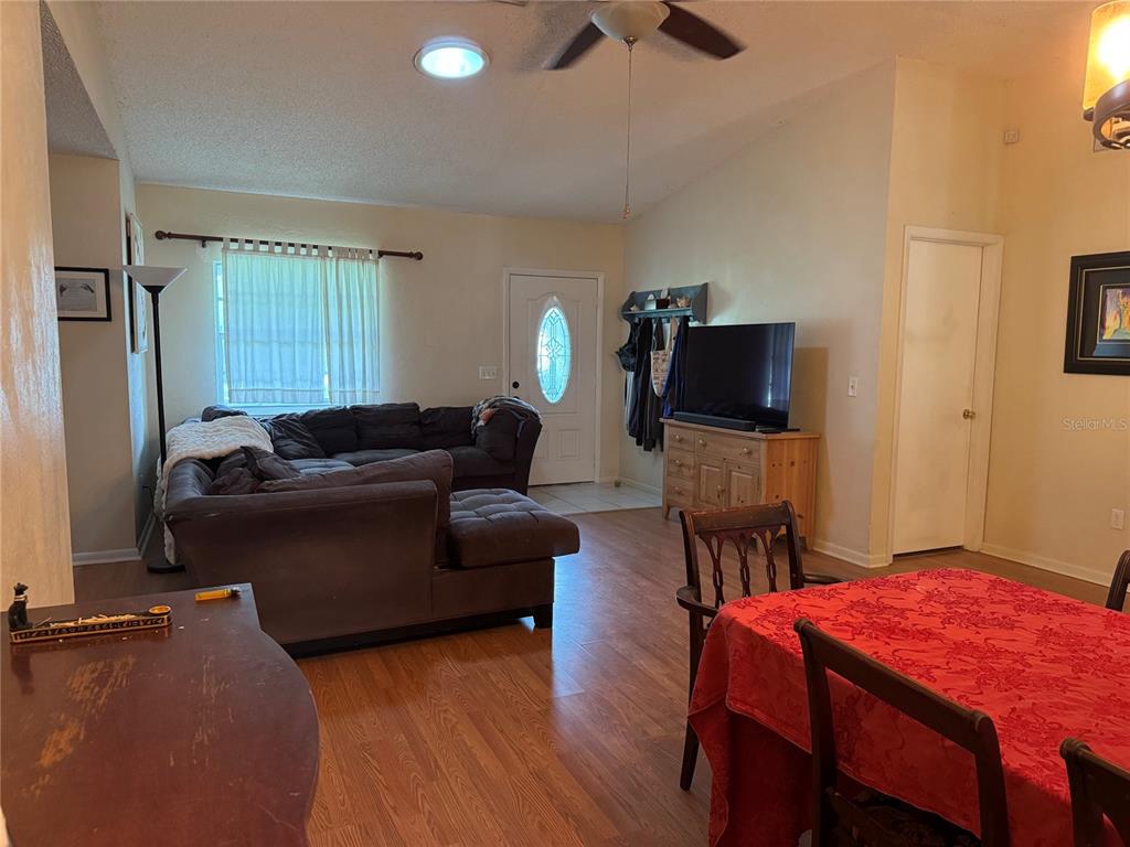 A living room and dining area feature wood-look flooring, a sectional sofa, and a television — 5 BANNER LANE, PALM COAST, FL
