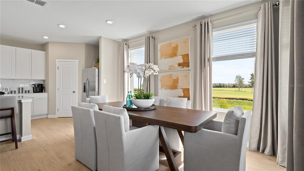 A dining room with a wooden table, upholstered chairs, and a view of a golf course — 167 GLENFIELD DRIVE, DAVENPORT, FL