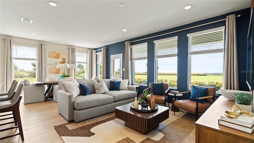 A living room features a grey sofa, two leather chairs, and large windows overlooking a field — 167 GLENFIELD DRIVE, DAVENPORT, FL