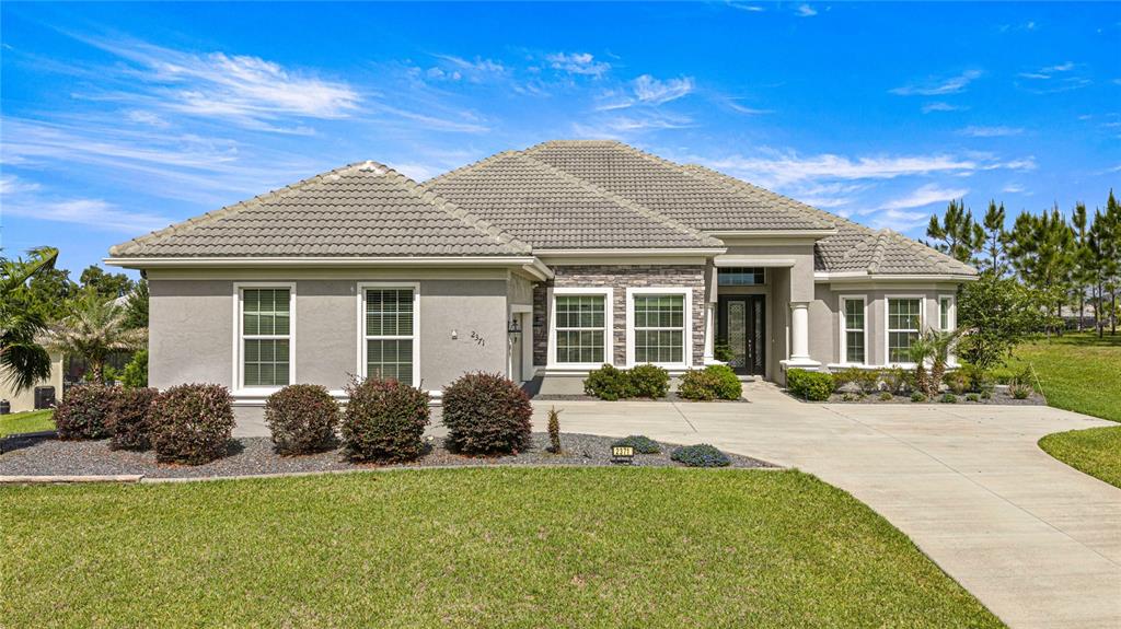 A single-story house with a gray stucco exterior, stone accents, and a tiled roof — 2371 N PEAKVIEW LOOP, HERNANDO, FL