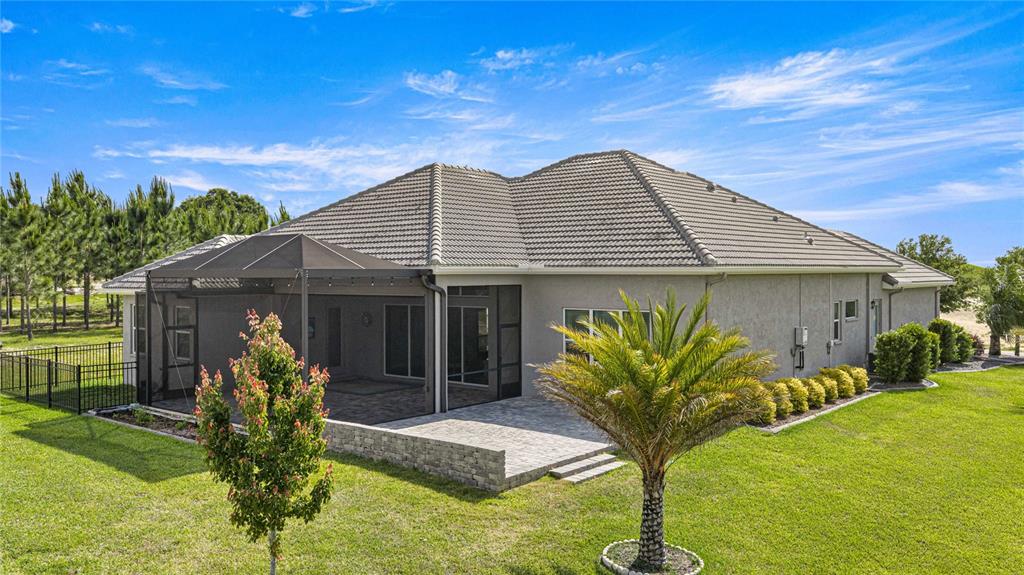 A single-story house features a tiled roof, a screened-in patio, and a paved outdoor area — 2371 N PEAKVIEW LOOP, HERNANDO, FL