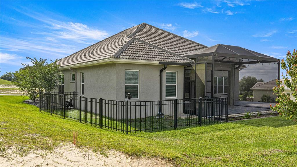 A single-story house with a screened-in patio and a black metal fence in the backyard — 2371 N PEAKVIEW LOOP, HERNANDO, FL