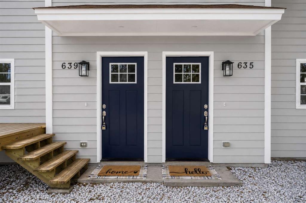 Two dark blue front doors with windows and house numbers sit side-by-side under a porch — 639 6TH AVENUE S, JACKSONVILLE BEACH, FL