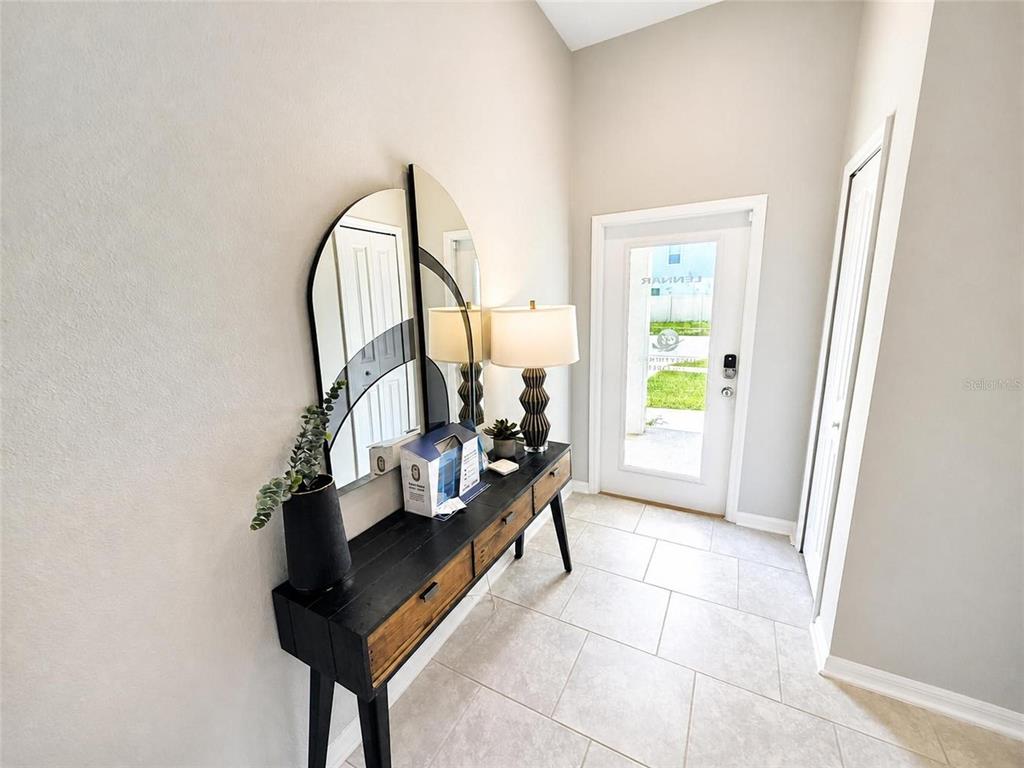 A foyer features a black console table, a decorative mirror, and a glass-paneled front door — 1104 TYLER LOOP, WINTER HAVEN, FL