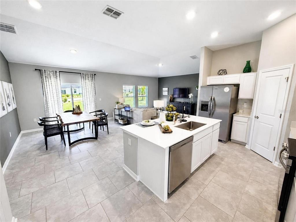 An open-concept kitchen and dining area features white cabinetry, a central island, and tile flooring — 1104 TYLER LOOP, WINTER HAVEN, FL