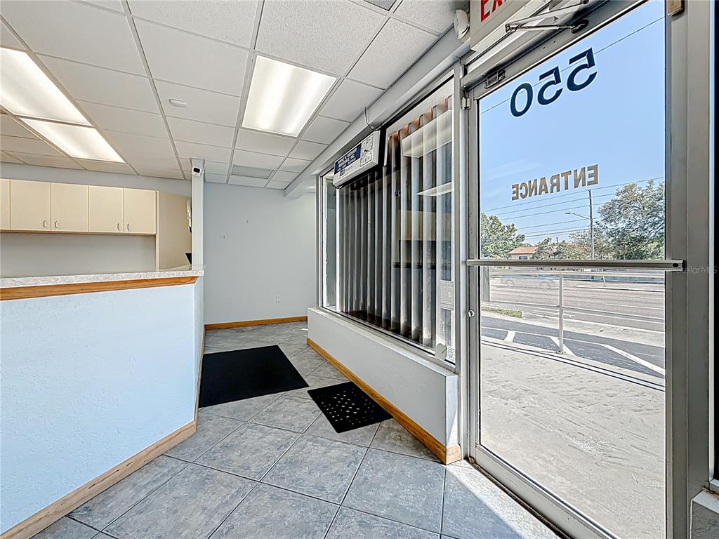 An office interior features a reception counter, tiled flooring, vertical blinds, and a glass entrance door — 550 E BAY DRIVE, LARGO, FL