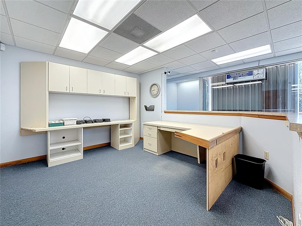 An office space features built-in cabinetry, a corner desk, blue carpeting, and a drop ceiling — 550 E BAY DRIVE, LARGO, FL