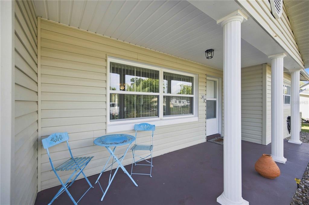 A covered porch features light-colored siding, white columns, and a small blue metal bistro set — 314 S JEFFERSON STREET, BEVERLY HILLS, FL