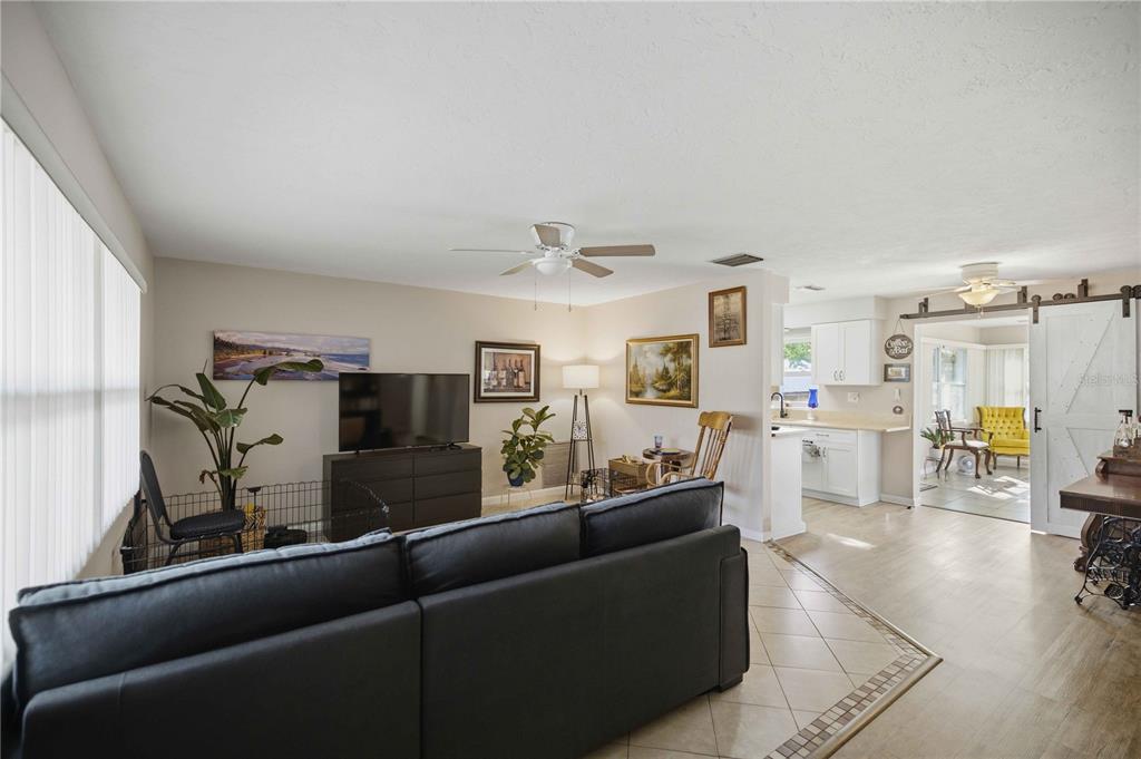 A living room with a black sofa, television, and an open transition to a kitchen — 314 S JEFFERSON STREET, BEVERLY HILLS, FL