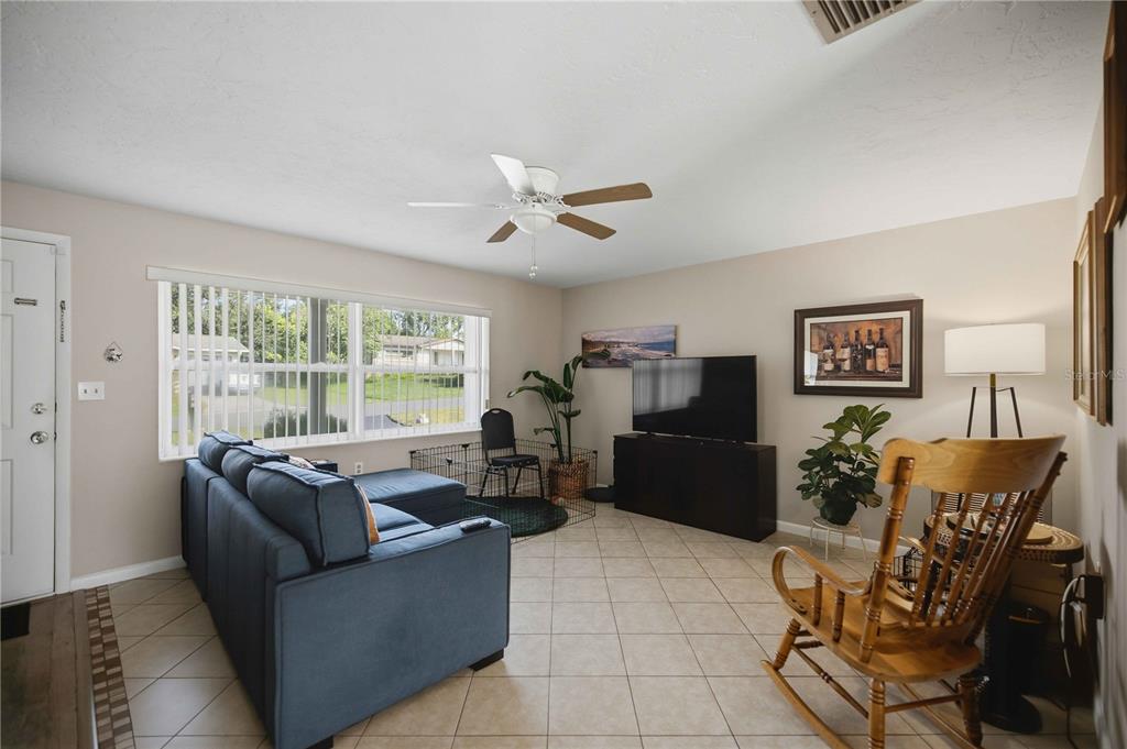 A living room features a blue sectional sofa, a television on a stand, and tile flooring — 314 S JEFFERSON STREET, BEVERLY HILLS, FL