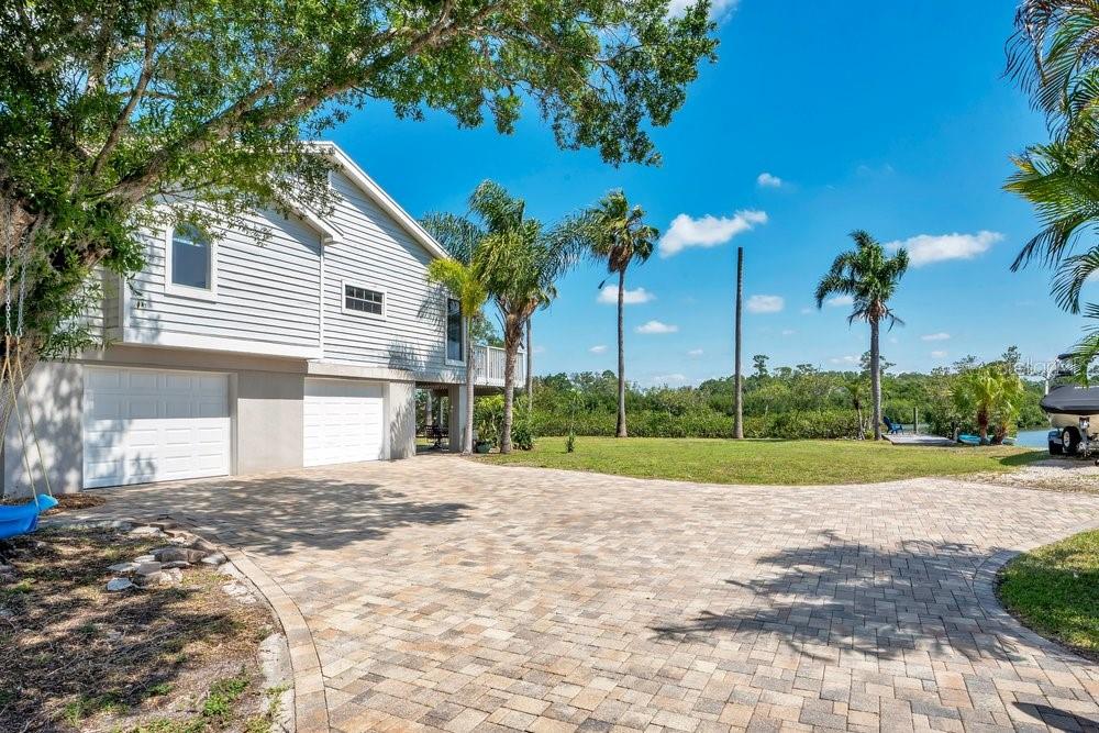 A two-story house with a paved driveway, two garage doors, and palm trees in Florida — 3858 SHORE BOULEVARD, OLDSMAR, FL