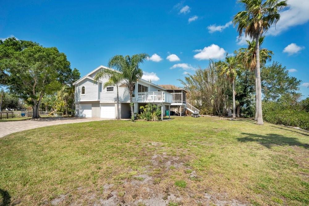 A two-story house with a white exterior, elevated deck, and attached garage sits on a lawn — 3858 SHORE BOULEVARD, OLDSMAR, FL