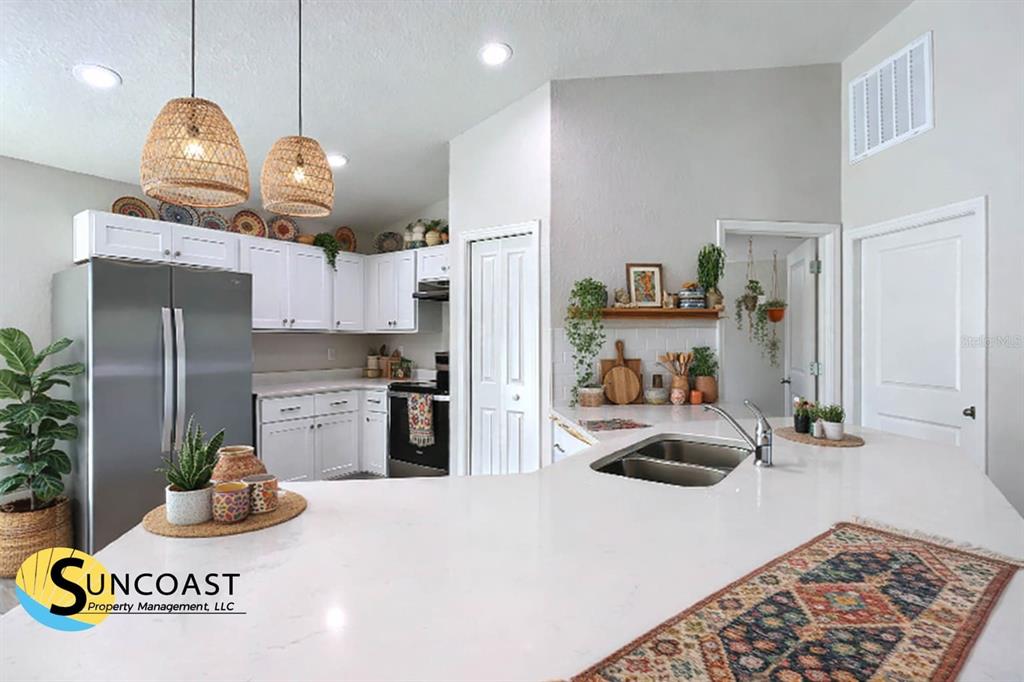 A bright kitchen features white cabinetry, stainless steel appliances, and a large white countertop island — 12063 SE 89TH AVENUE, BELLEVIEW, FL