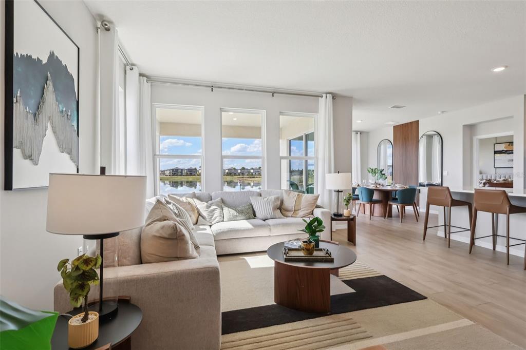A bright living room features a sectional sofa, a round coffee table, and large windows — 8595 HEMPSTEAD WAY, MOUNT DORA, FL