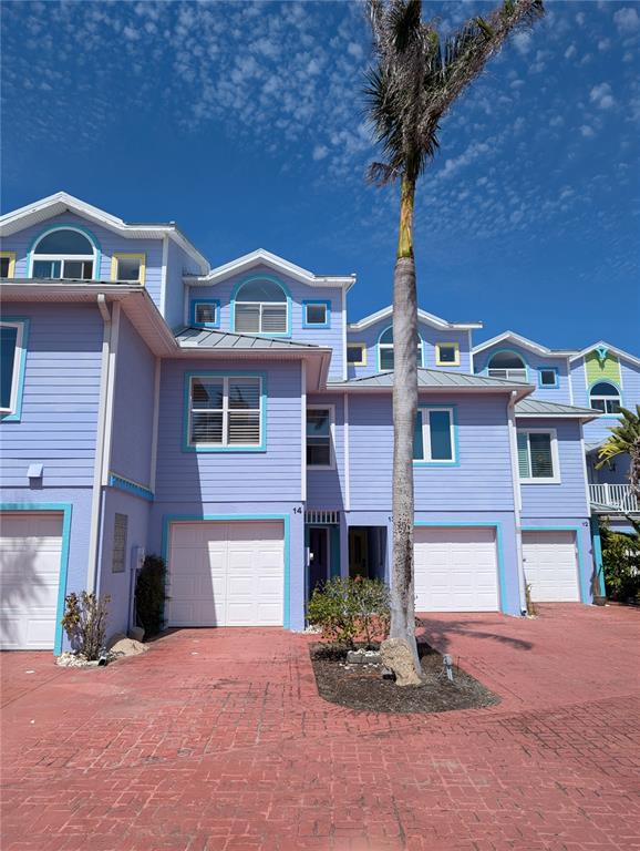 A row of light purple townhouses with white garage doors and a palm tree in front — 3000 OCEAN SHORE BOULEVARD UNIT 14, ORMOND BEACH, FL