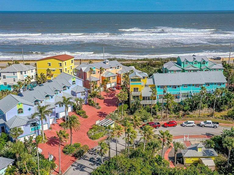 An aerial view shows colorful beach houses with gray roofs situated along a sandy coastline — 3000 OCEAN SHORE BOULEVARD UNIT 14, ORMOND BEACH, FL