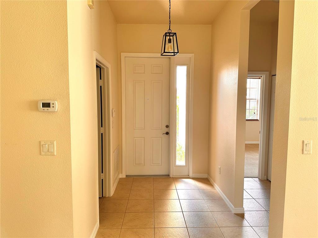 An entryway with tile flooring, a white front door, and a hanging pendant light — 4950 SANDY BROOK CIRCLE, WIMAUMA, FL