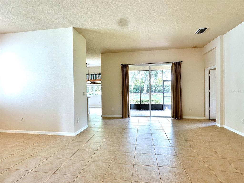 An open-concept living area features beige tile flooring, neutral walls, and sliding glass patio doors — 4950 SANDY BROOK CIRCLE, WIMAUMA, FL