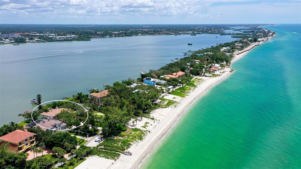 An aerial view shows a coastal property with a large house surrounded by lush trees — 1216 N CASEY KEY ROAD, OSPREY, FL