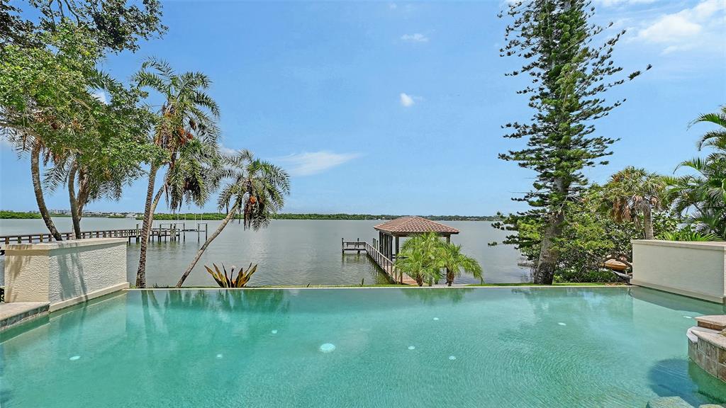 An infinity pool overlooks a calm bay with a private dock and gazebo — 1216 N CASEY KEY ROAD, OSPREY, FL
