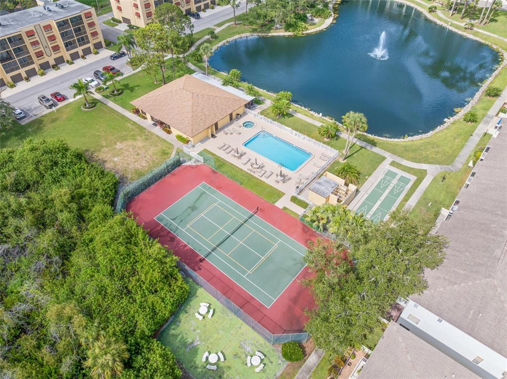 An aerial view of a multi-story apartment building with red shutters and attached garages — 5817 PARK STREET N UNIT 302, ST PETERSBURG, FL