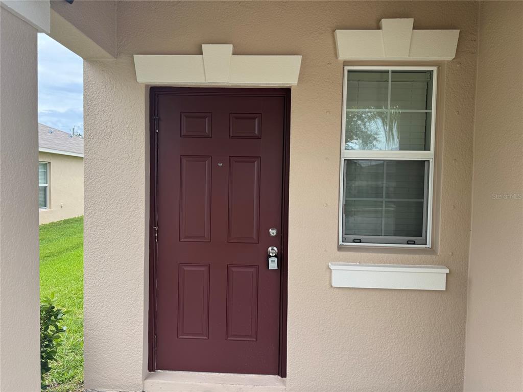A maroon front door with a lockbox and a window on a beige exterior wall — 405 SERENITY MILL LOOP, RUSKIN, FL