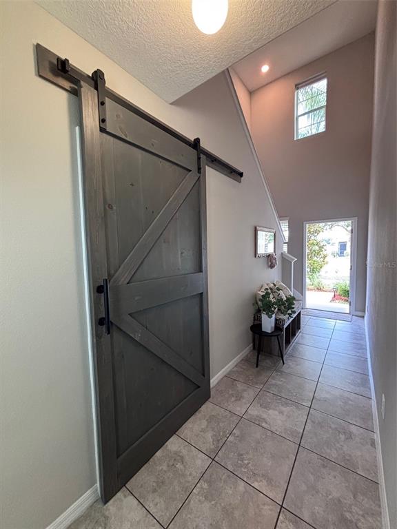 A hallway features a gray barn door, tile flooring, and a view toward an exterior door — 405 SERENITY MILL LOOP, RUSKIN, FL