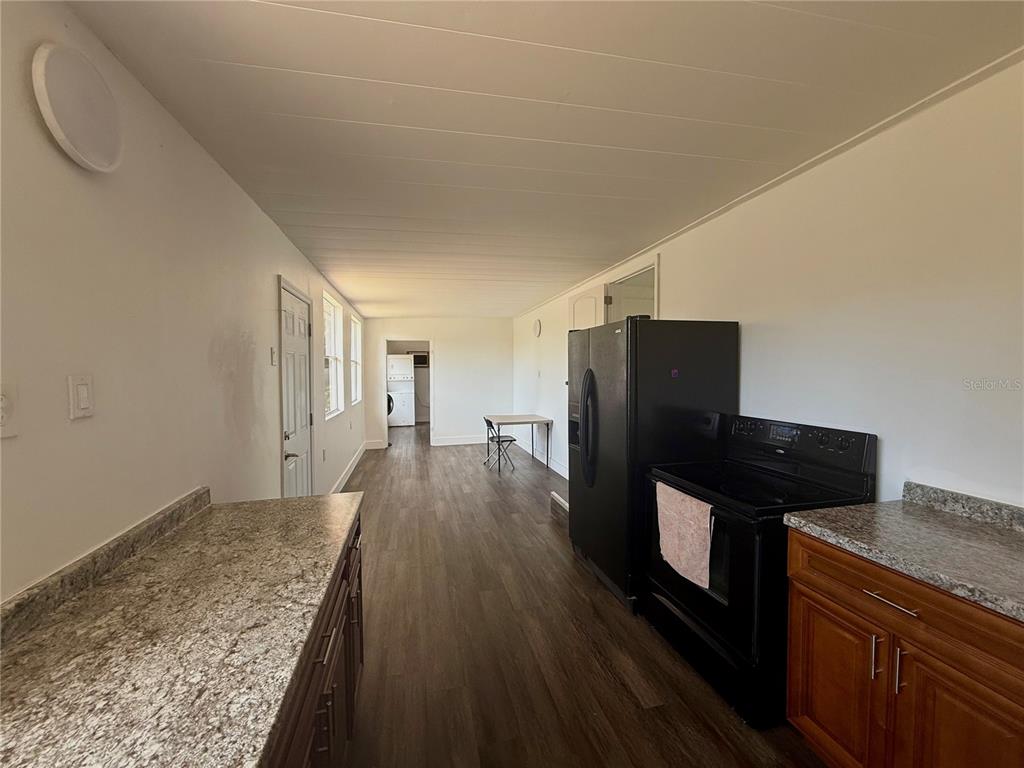 A kitchen with wood-look flooring, dark wood cabinets, granite countertops, and black appliances — 3603 SE 35TH AVENUE, OKEECHOBEE, FL
