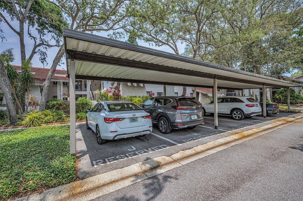 A covered parking area with three parked cars in front of a multi-story apartment building — 300 S FLORIDA AVENUE UNIT 200J, TARPON SPRINGS, FL