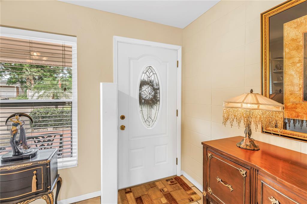 An entryway features a white front door with an oval glass insert and tile flooring — 7999 RIDGE ROAD, SEMINOLE, FL