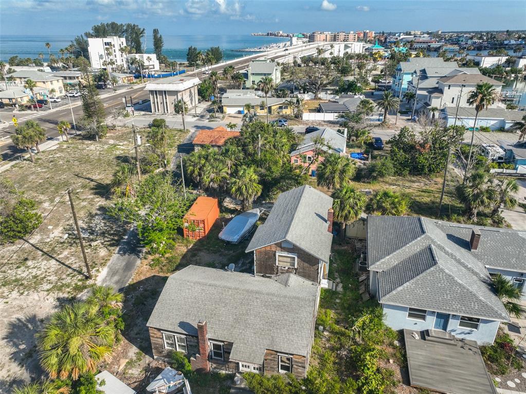 An aerial view shows a weathered house with a gray roof near a coastal road — 108 125TH AVENUE, TREASURE ISLAND, FL