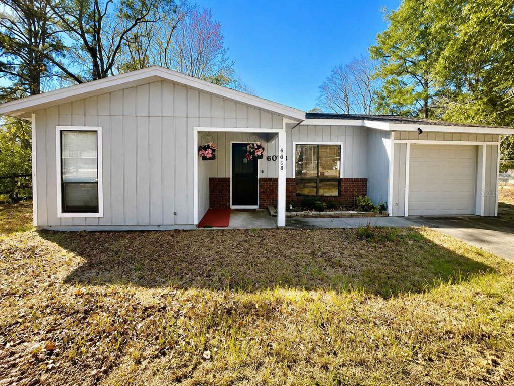 A single-story house with light gray vertical siding, a front porch, and an attached garage — 6018 NW 26TH TERRACE, GAINESVILLE, FL