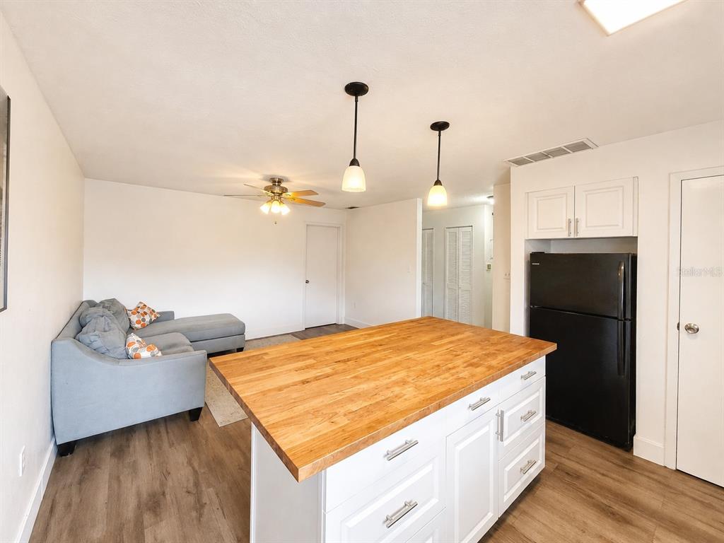 A kitchen island with a wood countertop sits in front of a living area — 2811 SW ARCHER ROAD UNIT Z242, GAINESVILLE, FL