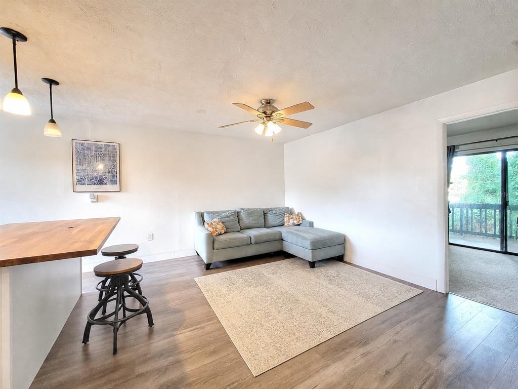 A living room features a light blue sectional sofa, a neutral area rug, and wood flooring — 2811 SW ARCHER ROAD UNIT Z242, GAINESVILLE, FL