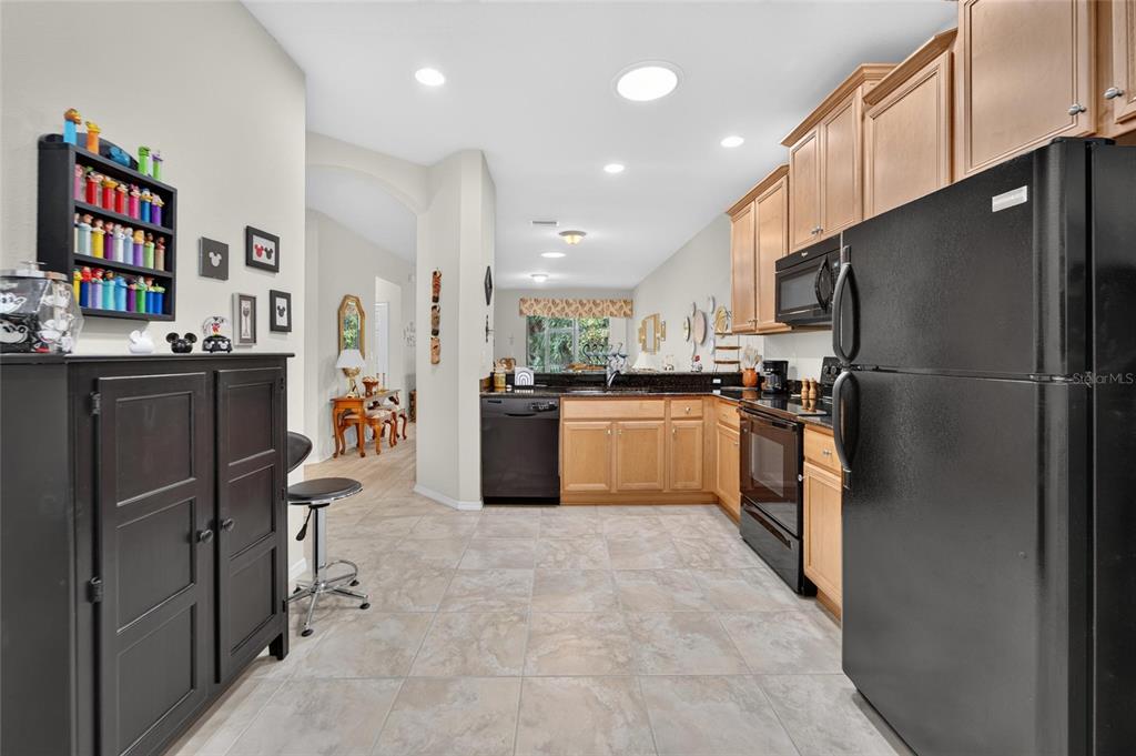 A kitchen features light wood cabinets, black appliances, and tile flooring — 428 SENECA FALLS DRIVE, APOLLO BEACH, FL