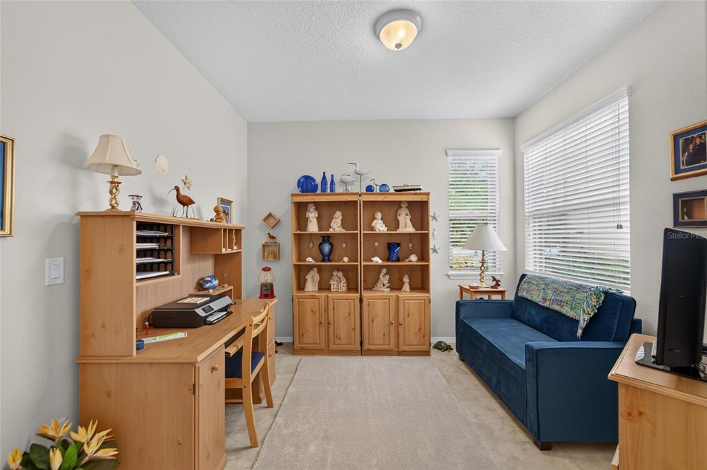 A home office features a wooden desk, matching shelving unit, and a blue sofa — 428 SENECA FALLS DRIVE, APOLLO BEACH, FL