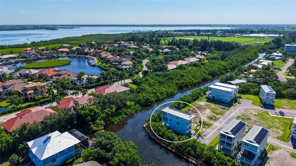 An aerial view shows a blue multi-story house situated along a narrow canal — 12435 DOCKSIDE TERRACE, CORTEZ, FL