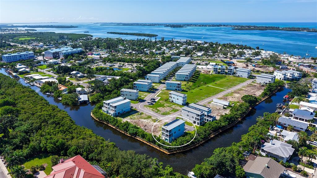 An aerial view shows a modern blue house circled in a residential waterfront community — 12435 DOCKSIDE TERRACE, CORTEZ, FL