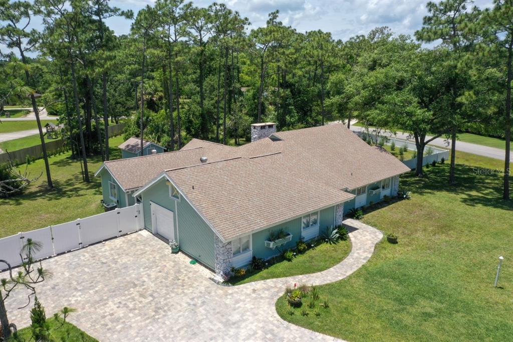 An aerial view of a light green house with a stone chimney and paved driveway — 213 RIVERBEND ROAD, ORMOND BEACH, FL