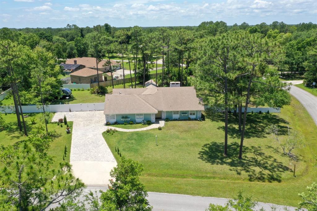 An aerial view shows a single-story house with a paved driveway and a large backyard — 213 RIVERBEND ROAD, ORMOND BEACH, FL