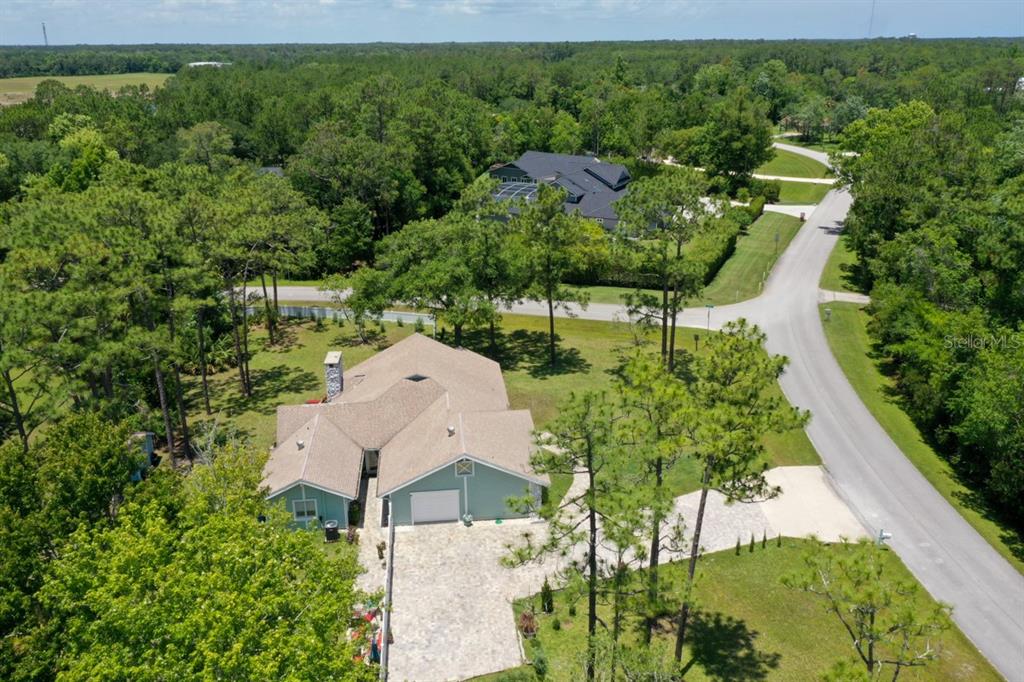 An aerial view shows a light green house with a tan roof and paved driveway — 213 RIVERBEND ROAD, ORMOND BEACH, FL