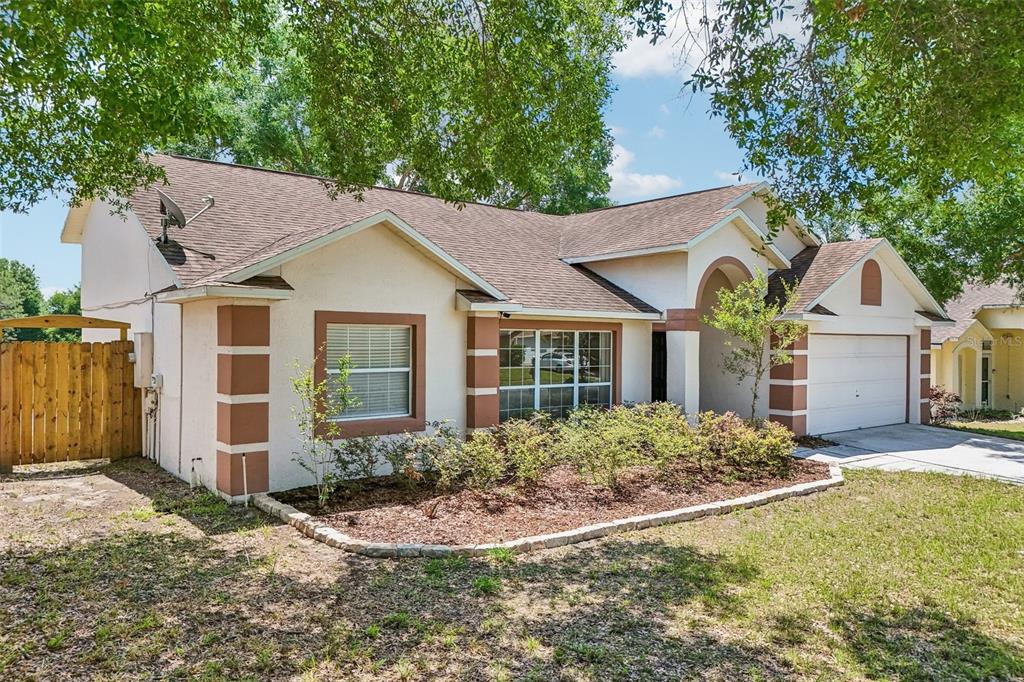 A single-story house with a tan stucco exterior, brown trim, and a two-car garage — 2596 ALCLOBE CIRCLE, OCOEE, FL