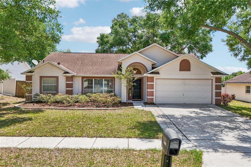 A single-story house with a brown roof, tan stucco exterior, and a two-car garage — 2596 ALCLOBE CIRCLE, OCOEE, FL