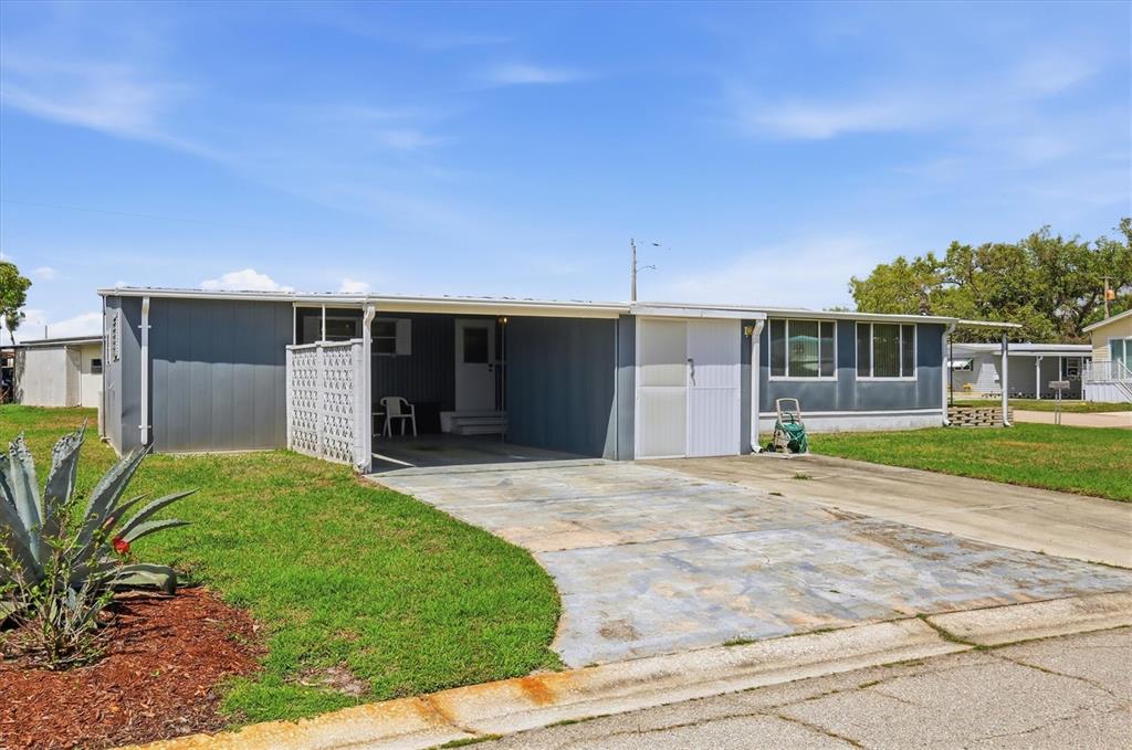 A single-story mobile home with gray siding, a carport, and a concrete driveway — 1112 46TH AVENUE DRIVE E, ELLENTON, FL