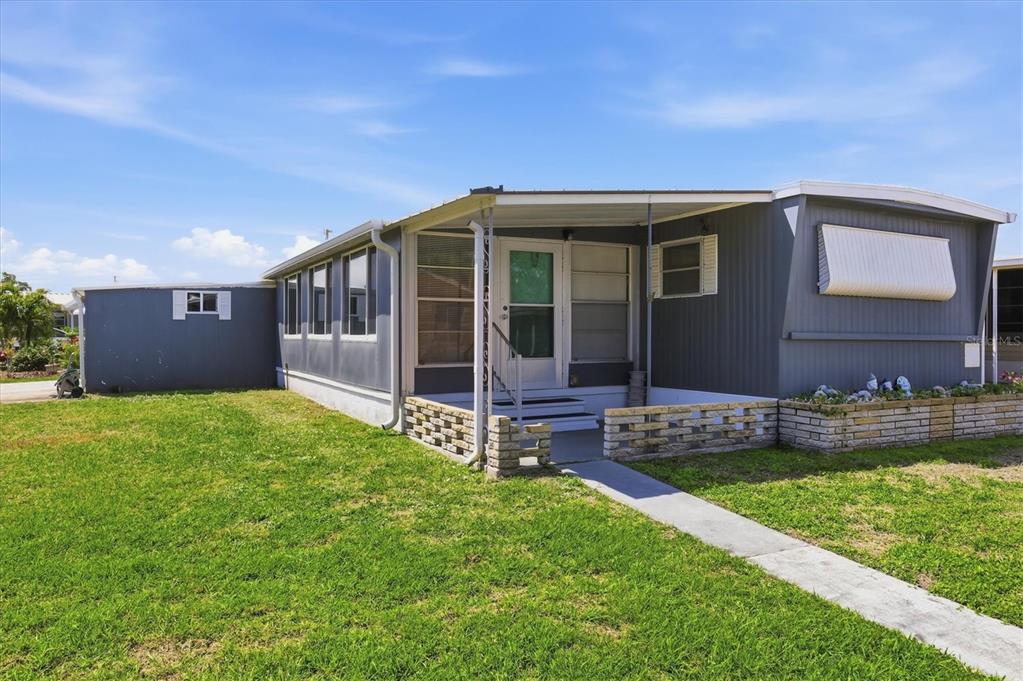 A gray mobile home with a covered front porch and a brick planter box — 1112 46TH AVENUE DRIVE E, ELLENTON, FL