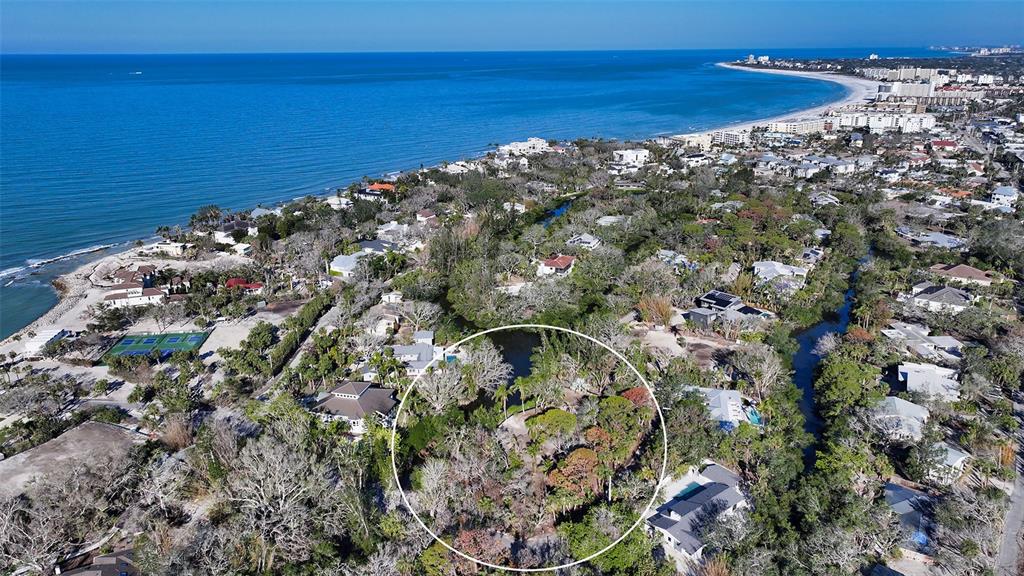 An aerial view shows a coastal neighborhood with a circled wooded lot near the ocean — 7340 PINE NEEDLE ROAD, SARASOTA, FL