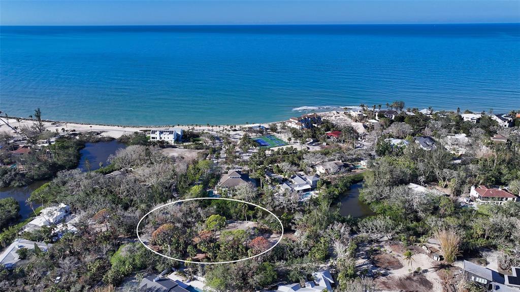 An aerial view shows a wooded, undeveloped lot surrounded by residential properties near the ocean — 7340 PINE NEEDLE ROAD, SARASOTA, FL