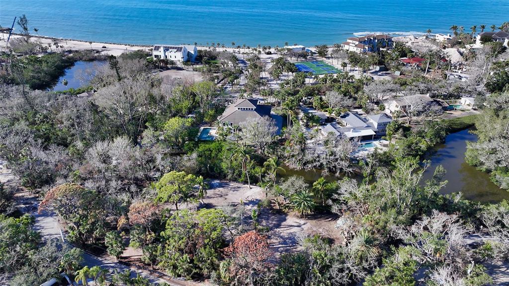Aerial view of a coastal property featuring lush vegetation, a pond, and nearby houses — 7340 PINE NEEDLE ROAD, SARASOTA, FL